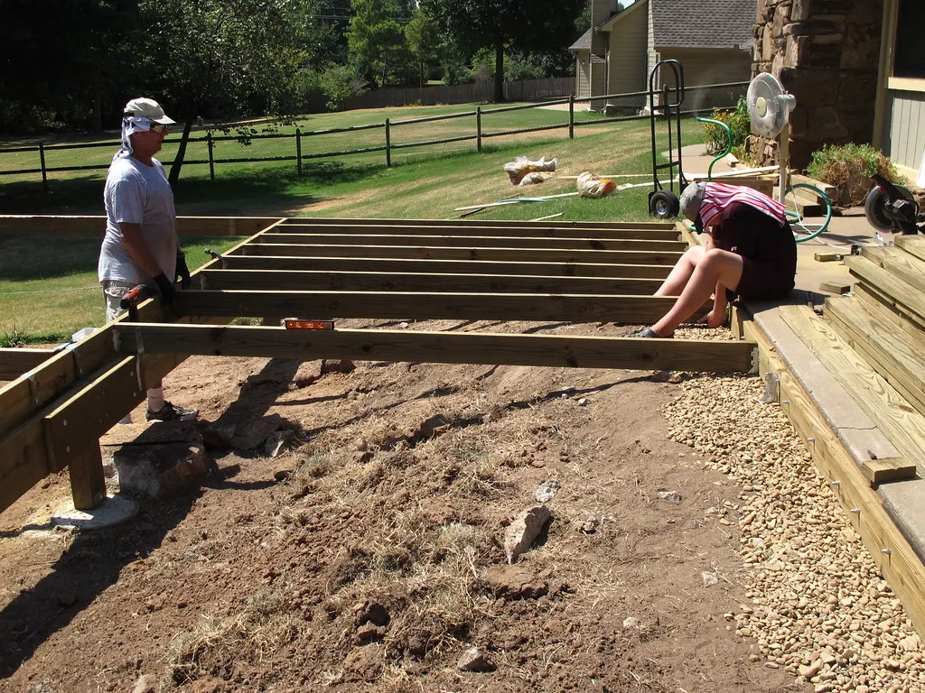 Two people framing a new deck in a backyard
