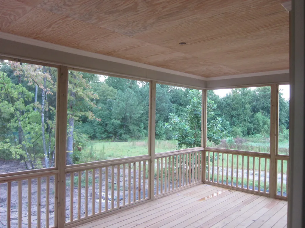 Covered porch with railings looking out at the yard